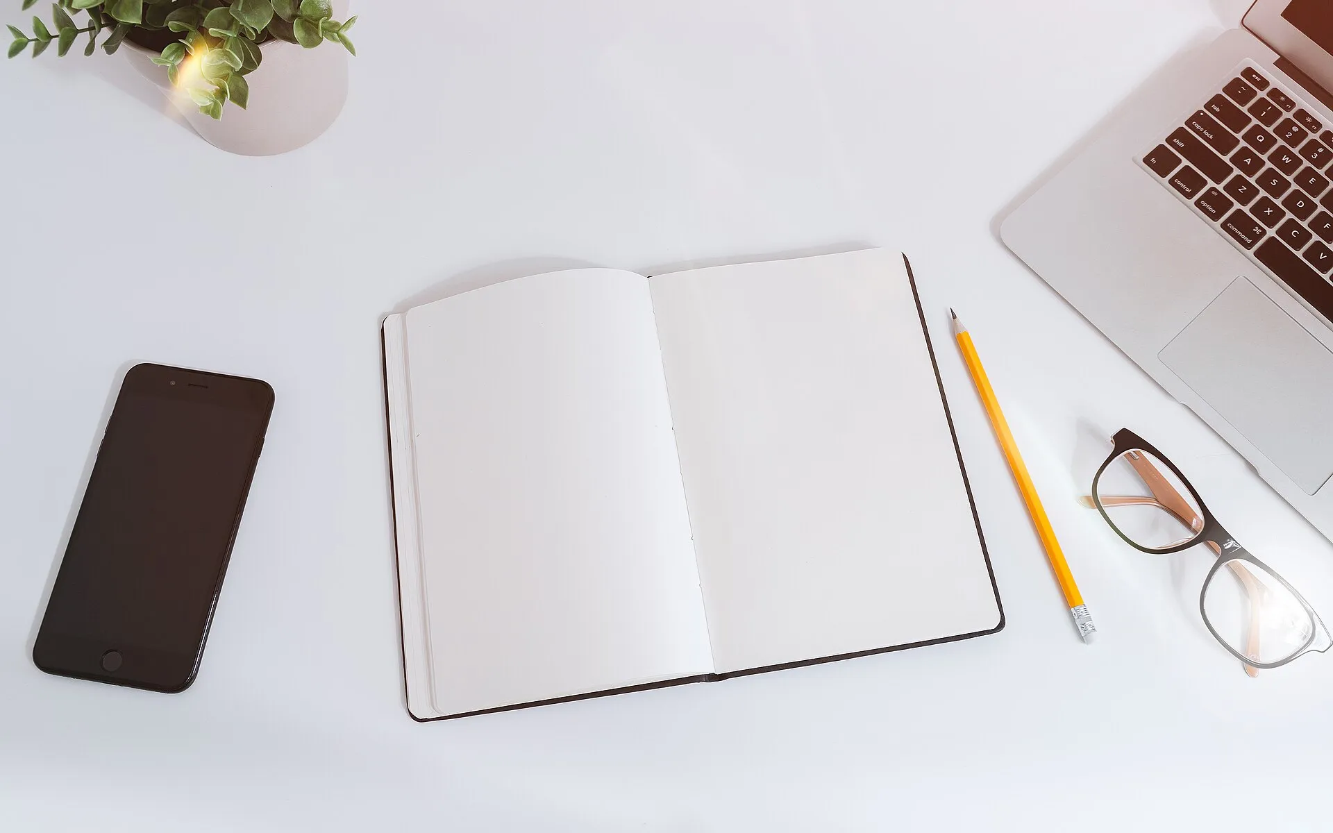 White work table with notes, smartphone and laptop